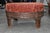 Beautiful hand-carved wooden footstool featuring a richly detailed frame with carved patterns and decorative metal banding...