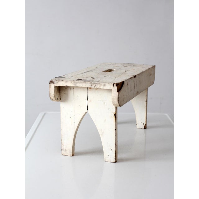 An antique early 20th century American farmhouse step stool with a beautifully worn white painted finish and a simple...