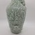 Celadon green glazed porcelain vase features an intricate relief design of lotus flowers, large leaves, and a small frog....