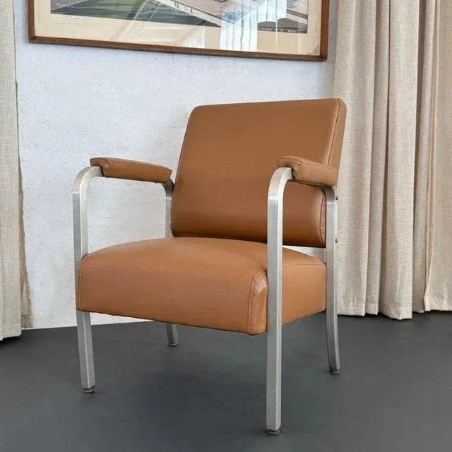 This mid-century machine-age armchair features a sleek brushed aluminum frame in an angular silhouette with seat, back and...