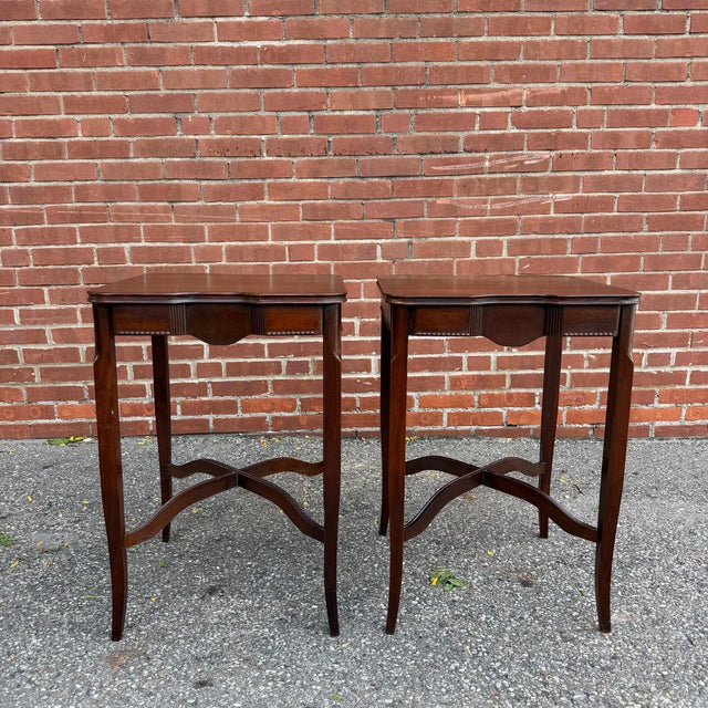 This pair of Edwardian-style mahogany occasional tables features softly shaped tops, molded edges, and elegant tapered...