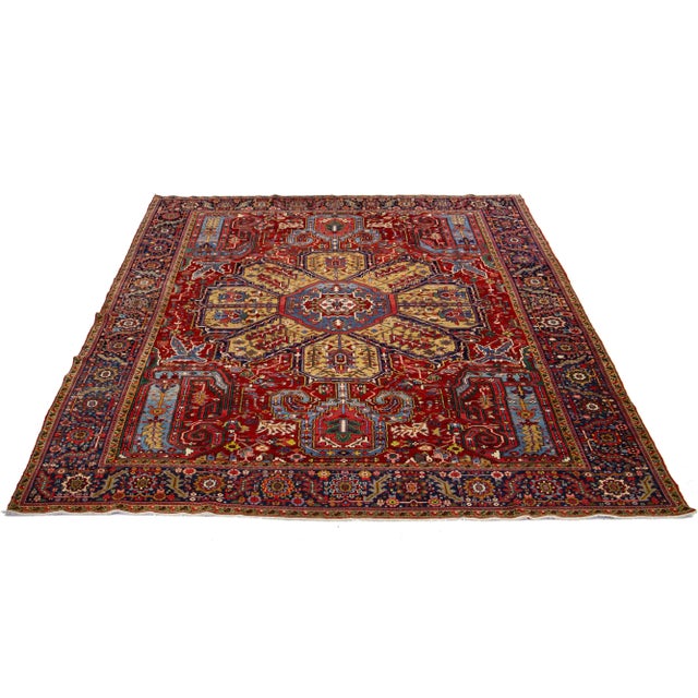 This is a beautiful antique Heriz hand-knotted wool rug featuring a red field. The Persian rug showcases a dark goldenrod...