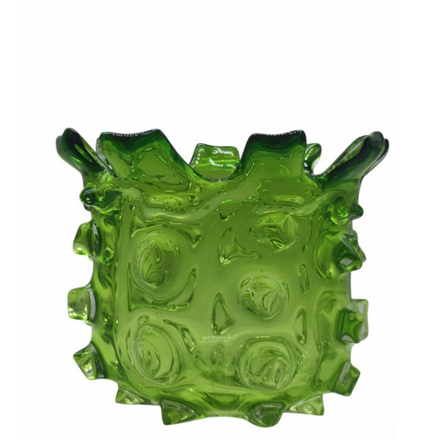 A sculptural vase crafted from vibrant grass-green glass, characterised by an incredible transparency that creates...