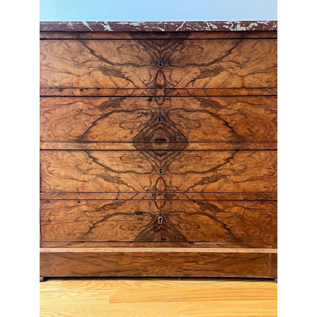Antique French commode in hand-veneered, book-matched walnut, with a mirrored, flame-like pattern across drawer fronts and...