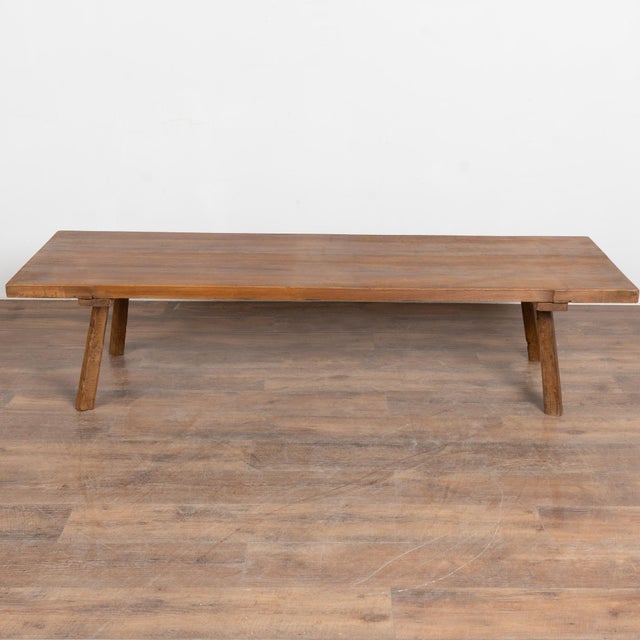 Early 20th-century walnut coffee table from Hungary featuring a dark finish and square peg legs that splay slightly...