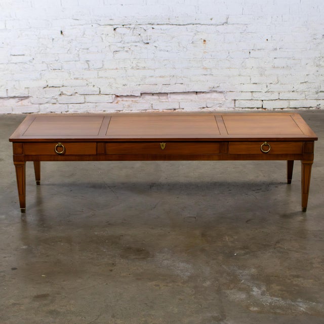 Marvelous vintage Neoclassic coffee table composed of a long, fairly low walnut toned hardwood frame with 3 section carved...