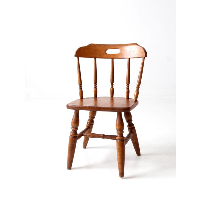 A charming mid-century children's chair in the Early American style, featuring turned spindle supports, turned legs, and a...