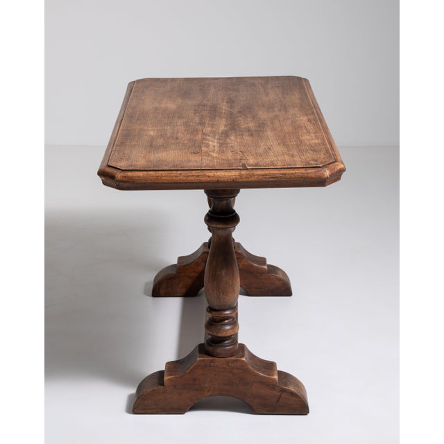 A character-rich oak side table retaining its original patina, showcasing the wear and history of the piece. The aged...