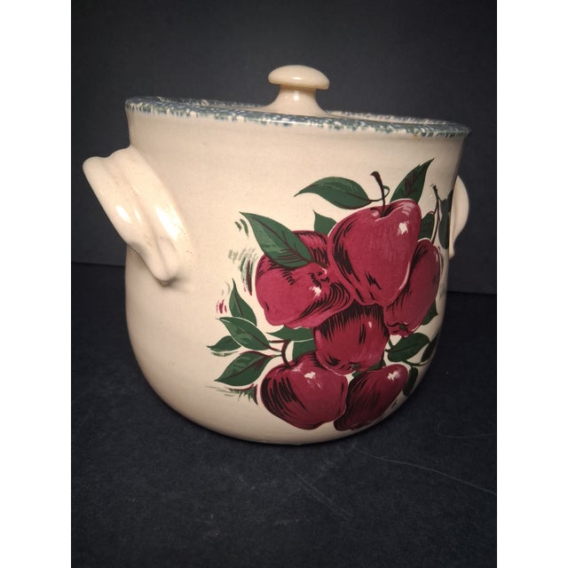 Home & Garden Party apple-patterned stoneware bean pot featuring a cream-colored glazed body with a cluster of red apples...