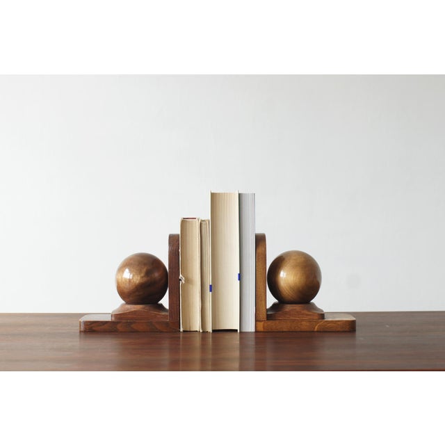 A pair of wooden bookends with a distinctive, geometric form. Each bookend consists of a heavy, rectangular base and a...