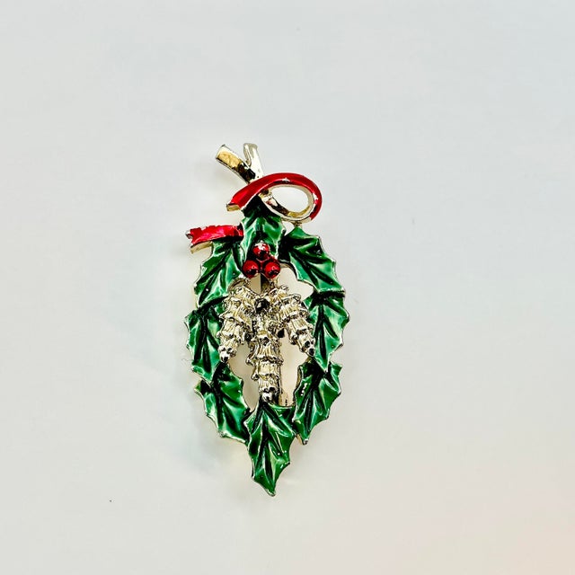 A lovely Christmas Brooch from Gerry’s Creatives from the 1950s. It features a green elongated holly wreath with red...