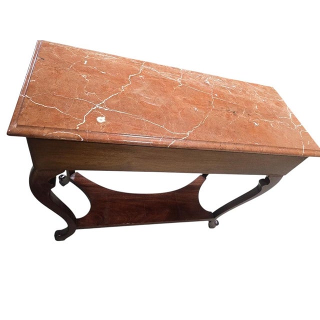An elegant French Empire-style console table featuring a genuine polished red marble top, carved floral drawer pulls,...