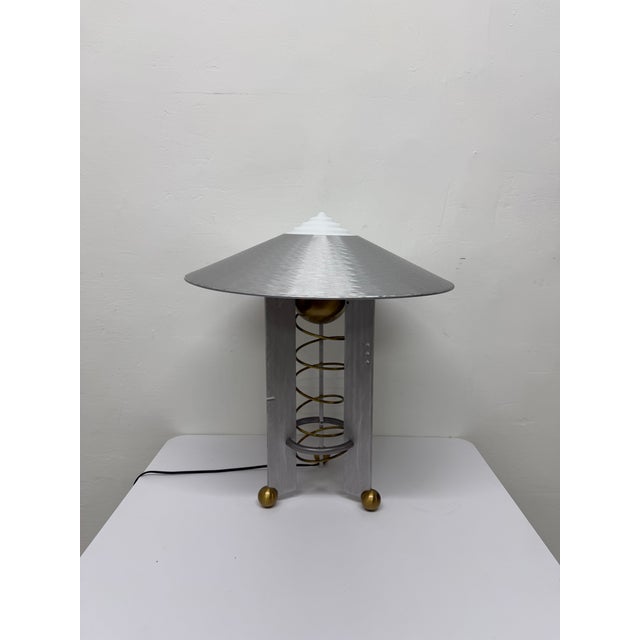 Modernist Art Deco inspired table lamp consisting of an aluminum frame and shade with a milk glass top diffuser and brass...