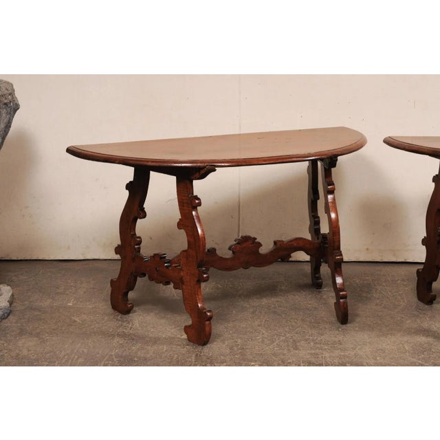 An Italian pair of beautifully-carved, lyre leg console tables from the early 19th century. These antique tables from...