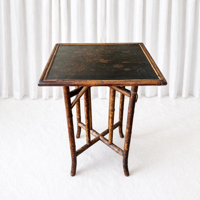 A beautifully aged antique side table featuring classic Chinoiserie lacquer work and faux bamboo construction. The square...