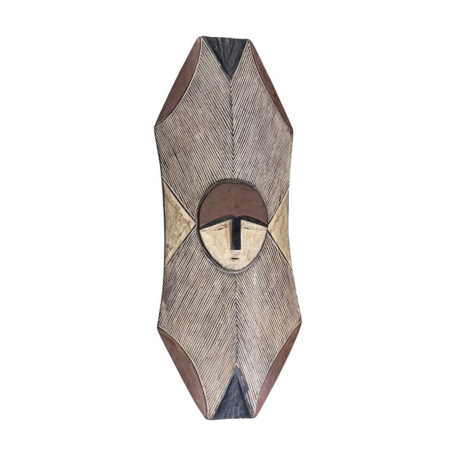 A vintage hand-carved shield from the Bamileke people of Cameroon, meticulously carved from a single piece of wood. This...