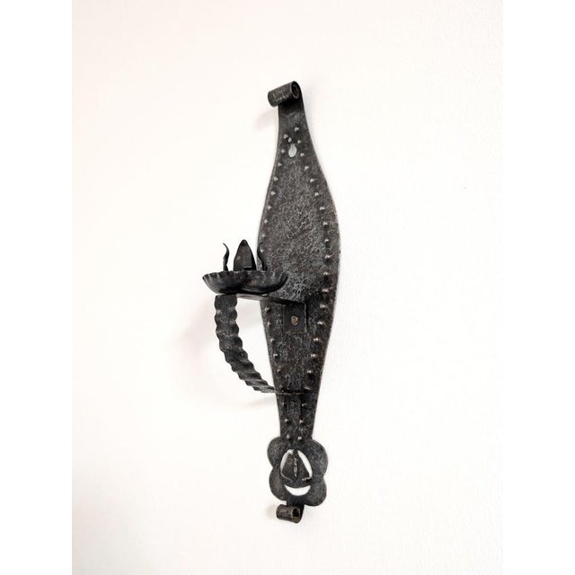 Spanish brutalist wrought iron candle wall sconce. This vintage iron wall lighting piece is hand forged with a hammered...
