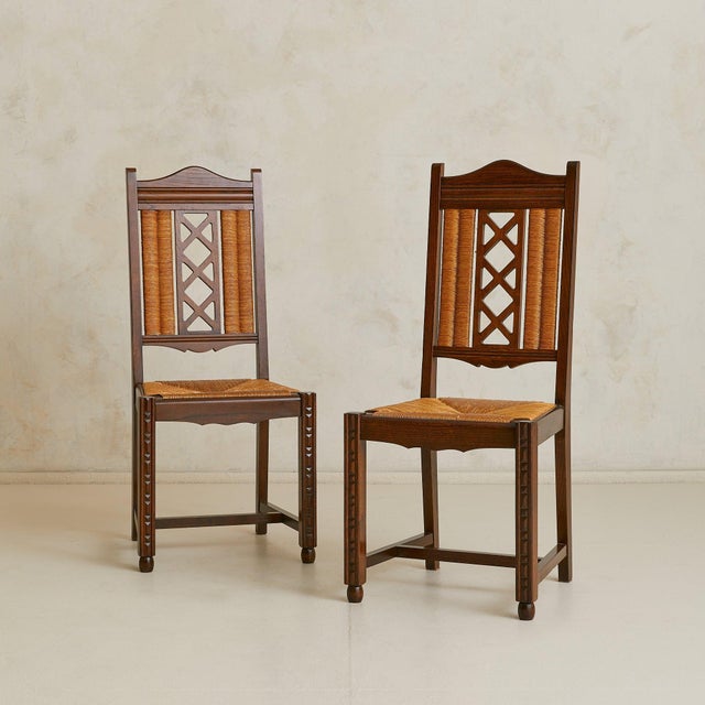 A set of six French dining chairs dating to the 1940s, crafted in oak with handwoven rush seats. The tall backs feature...