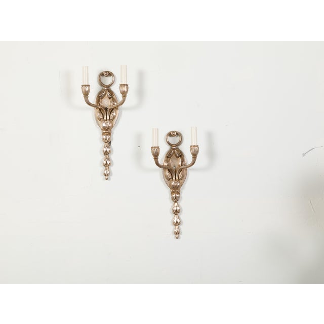 A pair of English vintage silver plated wall sconces from the mid 20th century, with two lights and foliage motifs....