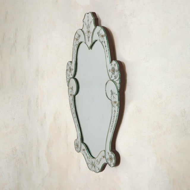 An Italian Art Deco Venetian wall mirror from the 1930s. Its silhouette is soft and ornate, framed in hand-cut, beveled...