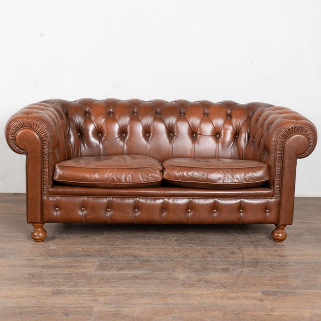 The soft patina of the brown vintage leather captures your attention in this wonderful Chesterfield loveseat or two seat...