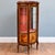 An elegant Louis XV style display cabinet with a glazed door and curved glazed sides. The cabinet has two glass shelves...