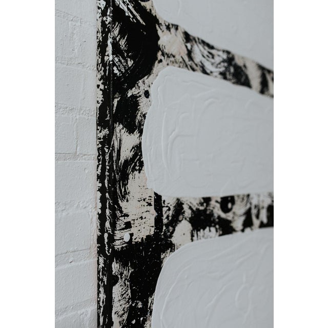 The longer you look at this black and white (with hints of tan) abstract painting the more you see. It has thick texture...