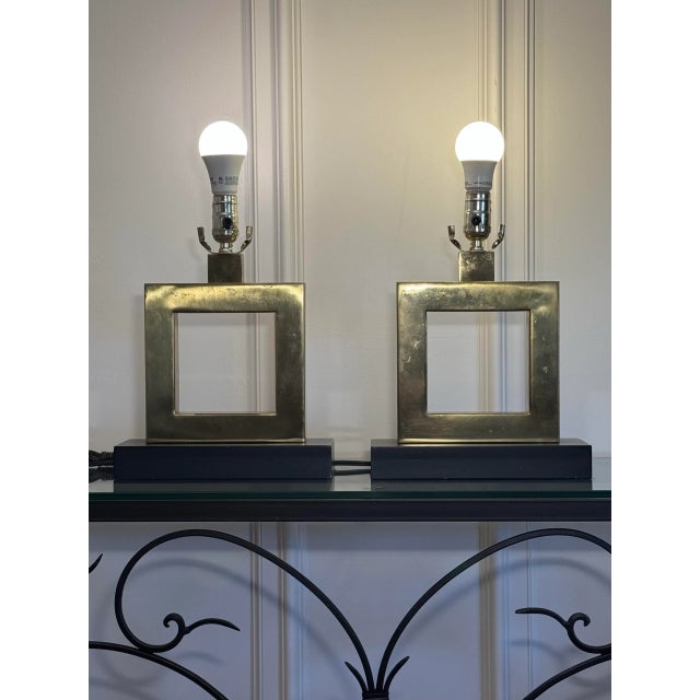 This pair of table lamps have a striking geometric design. The body consists of a square brass frame with an open center,...