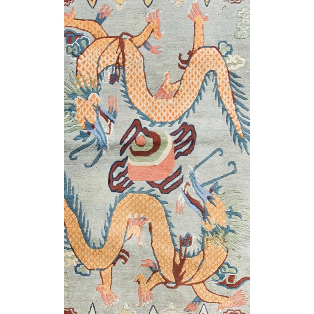 A striking late 20th century Tibetan hand-knotted wool rug with double dragons swirling around a pearl of truth, and with...