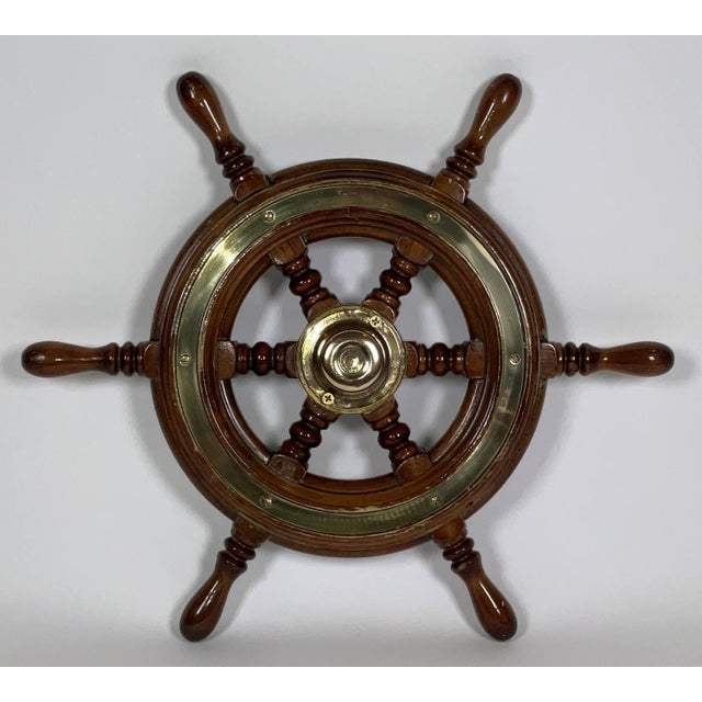 Six spoke ships wheel by Simpson Lawrence of England. Varnished wood frame with inlaid brass trim rings and brass hub cap....