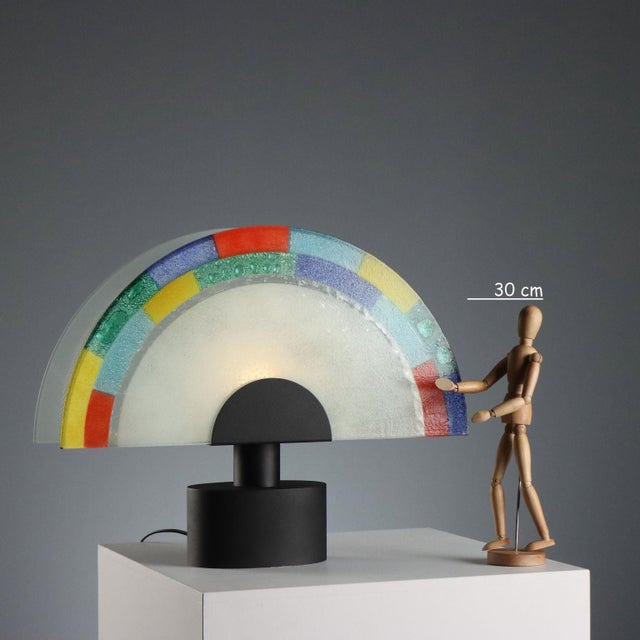 Table lamp crafted from Murano glass, dating back to the 1980s, featuring a semicircular design that captures the artistic...