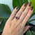 A 2.96-carat oval purple garnet glows in a rich grape-purple at the center of this solid 14K yellow gold ring, flanked by...