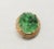 This is part of Chairish’s Costume Jewelry assortment. 1965 oval goldtone carved faux-jade brooch with security clasp....