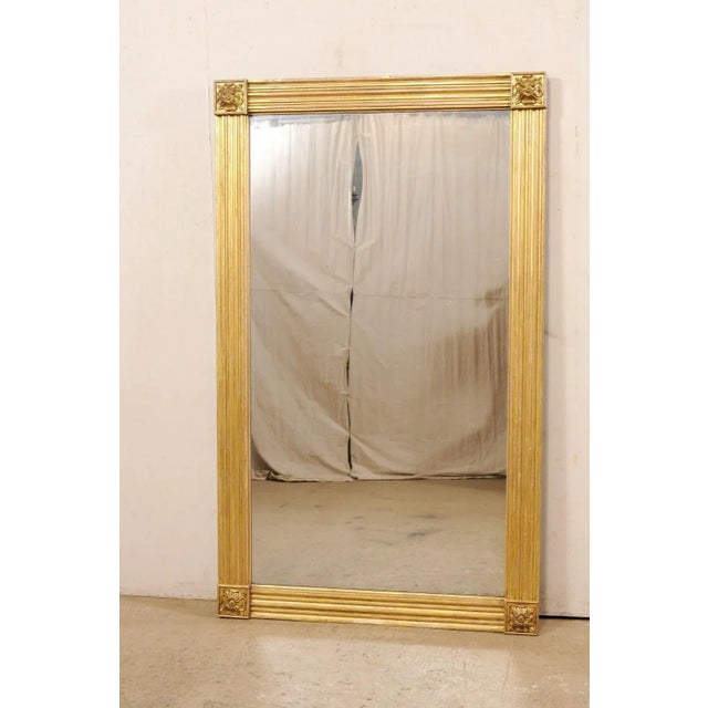 A tall English wood-carved mirror with gold gilt finish from the mid 19th century. This antique mirror from England, which...