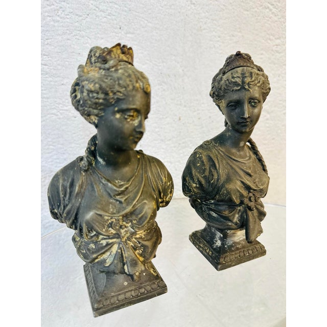 This small pair of classical-style busts are vintage figurines, likely made of spelter (a zinc alloy often used for...