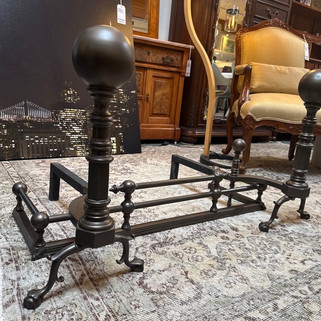 Design Plus Gallery presents a Pair of Andirons and Fender for the Fireplace. They have an oil rubbed tone to their metal...
