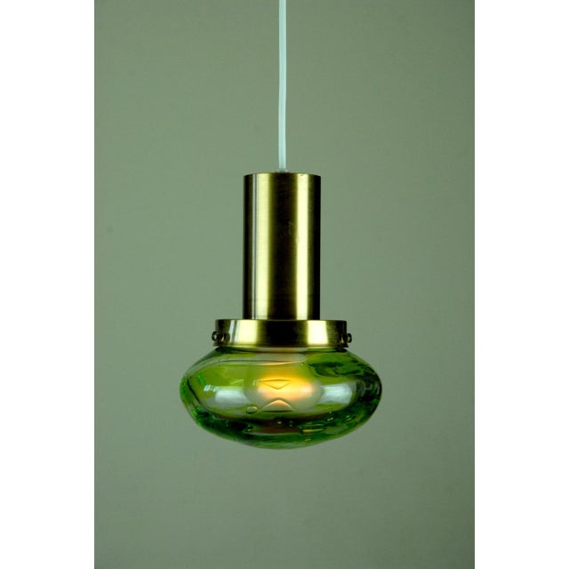 Pair of pendant lamps by Flygsfors, Sweden. Thick hand-blown glass by Paul Kedelv. They feature a swirled patterned green...