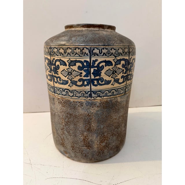 Vintage ceramic vessel featuring a classic Mediterranean-inspired form with a hand-decorated blue and white ornamental...