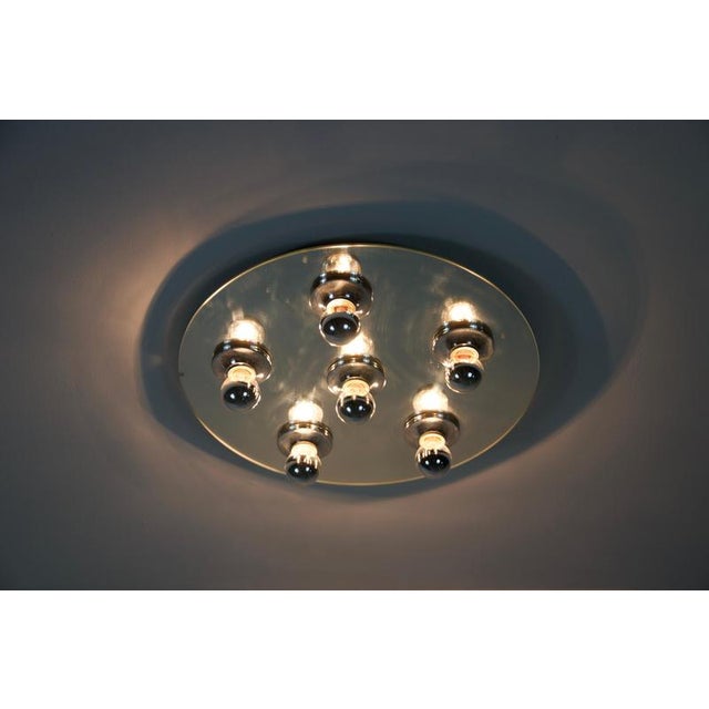 This unique ceiling lamp from the 1970s features a striking round design with a chrome finish and a mirrored surface,...