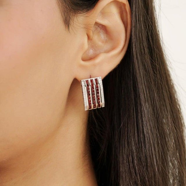 Crafted in 925 sterling silver, these elegant bar earrings feature natural round garnet gemstones measuring 2 mm, arranged...