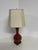 A classically designed ginger jar-style table lamp with a glossy oxblood red or deep burgundy glazed ceramic base in a...
