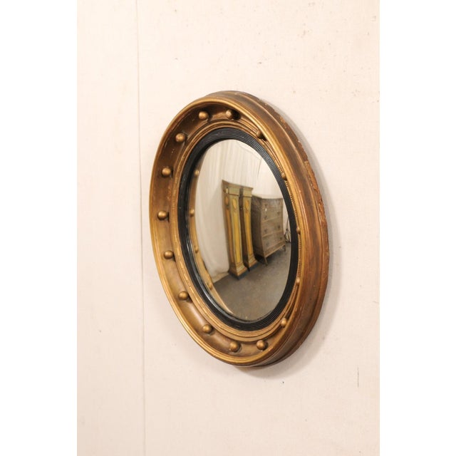 An American carved-wood bullseye accent mirror in black and bronze/gold, from the 19th century. This antique mirror...