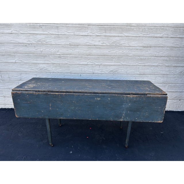 Classic deep-blue painted wood drop leaf table. Beuatifully designed and in excellent condition. Legs on wheels. Length...