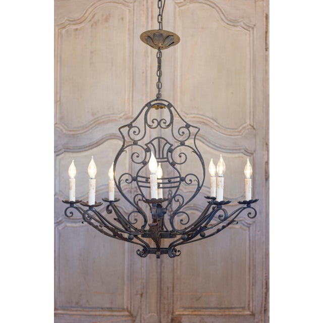 A French wrought iron eight light chandelier from the 20th century with scrolling motifs and acanthus leaves. This French...
