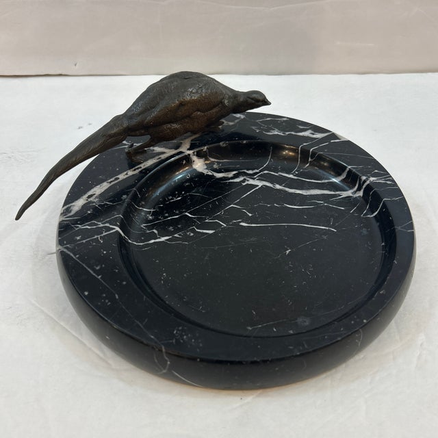 Wonderful solid black with white vein marble catchall with a bronze peacock attached to it. The scoop in the round marble...