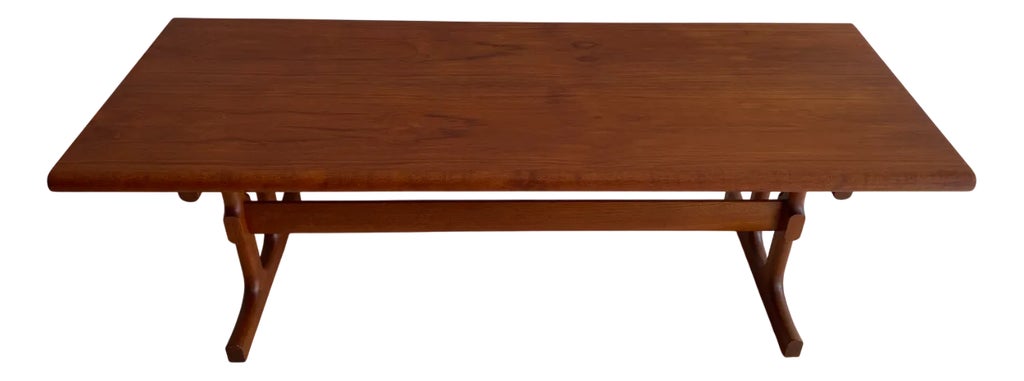 Wooden couch table with trestle legs on a white background.
