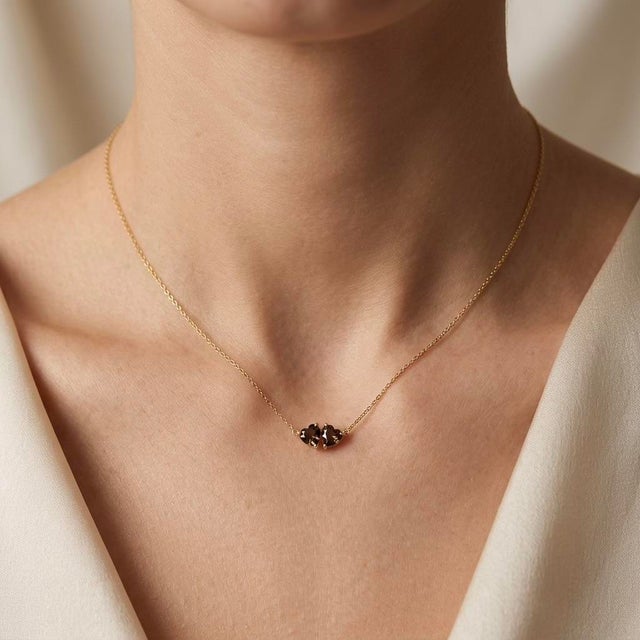 Bring grounded mystery to your style with this rich two-stone pendant necklace, featuring two sparkling smoky-brown heart-...