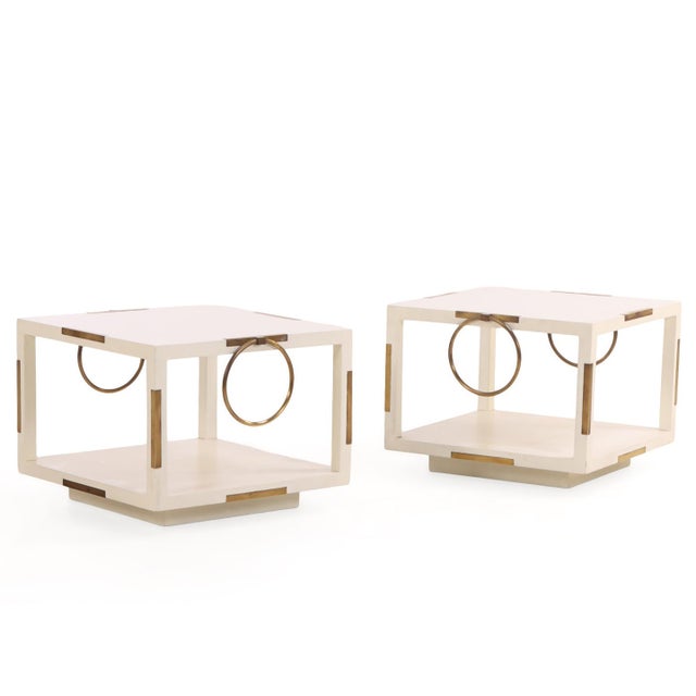 A rare pair of elegant two-tier end tables, in the manner of Parzinger, featuring a refined combination of white lacquered...