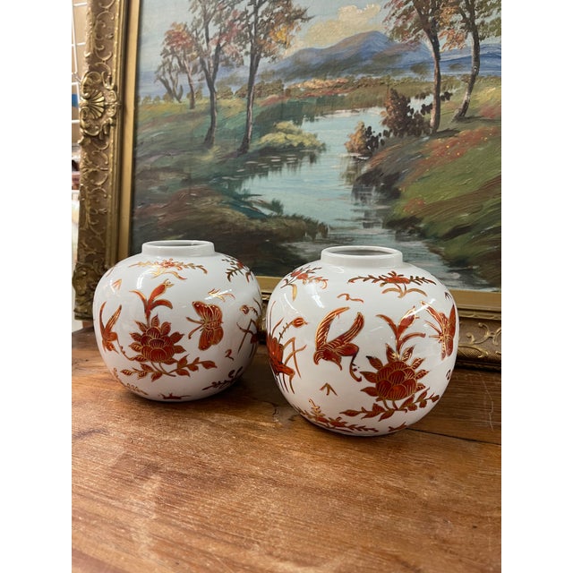 This matching pair of porcelain vases features a rounded, globular form decorated with stylized birds,butterflies, and...