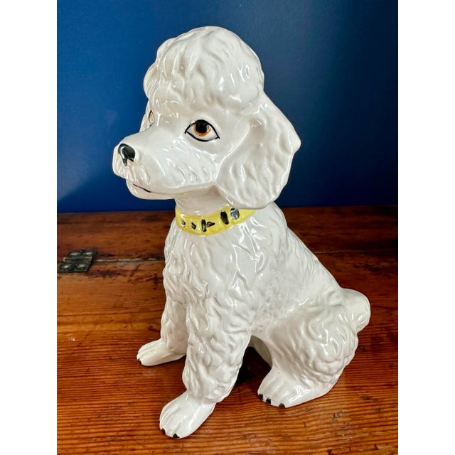 Very cute figurine of a white poodle with a yellow collar. Stamped Japan on the bottom.
